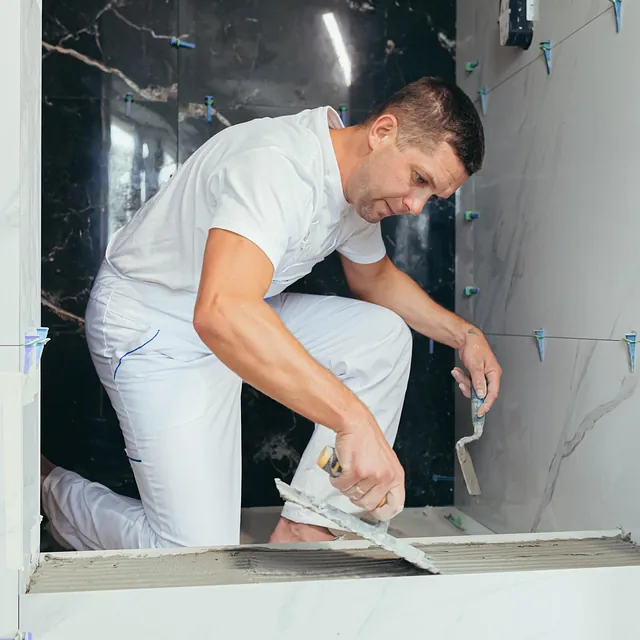 Mann i hvite klær legger fliser