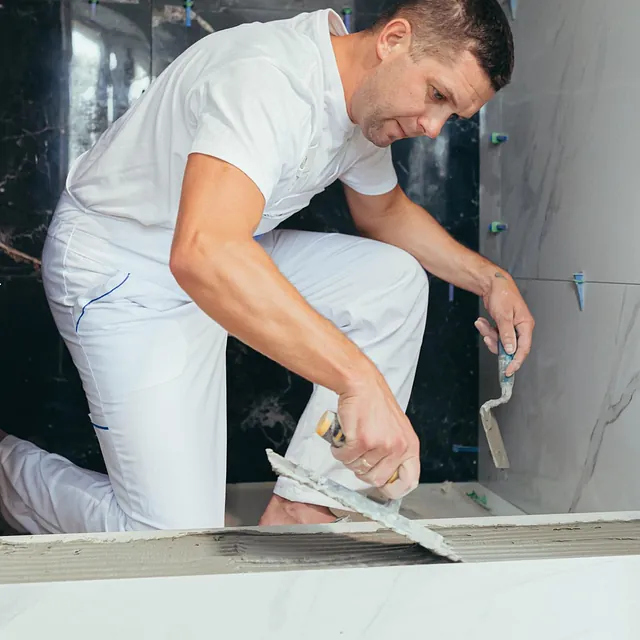 Mann i hvite klær legger fliser