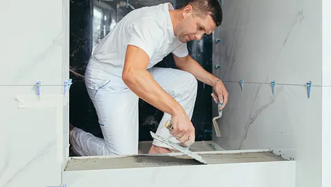 Mann i hvite klær legger fliser